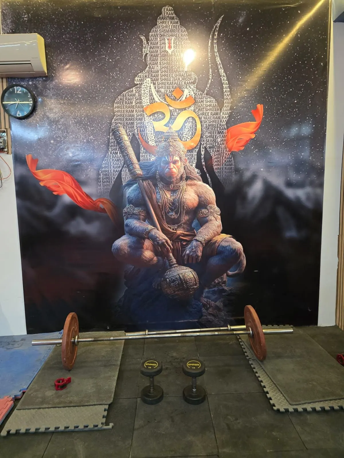 Free weights area with a barbell and dumbbells set out on floor mats